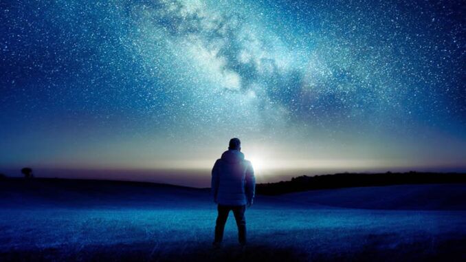 Mann schaut zur Milchstraße bei Nacht